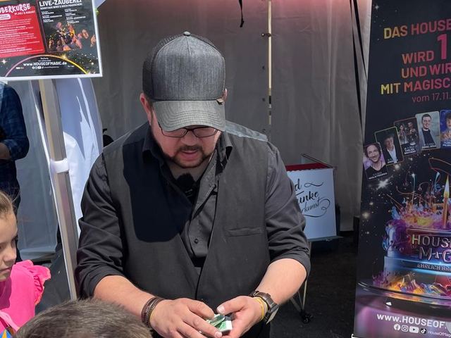 Fred Funke zeigt Kindern am Stand von House of Magic einen Trick aus nächster Nähe