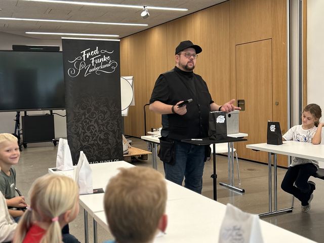 Fred Funke zaubert für Kinder an langen Tischen