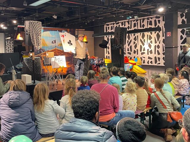 Kinder und Eltern verfolgen Fred Funkes Show in einer Piratenkulisse