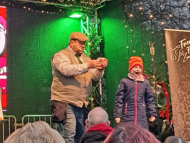 Fred Funke mit einem Kind auf der Bühne eines Weihnachtsmarkts