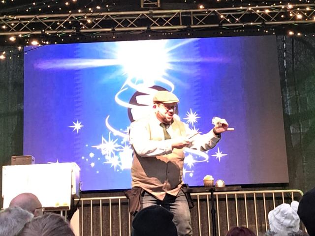 Fred Funke auf einer Weihnachtsmarktbühne vor einer großen Leinwand