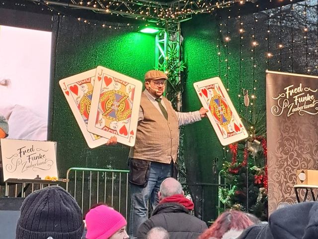 Fred Funke mit Riesenspielkarten auf einer Weihnachtsmarktbühne